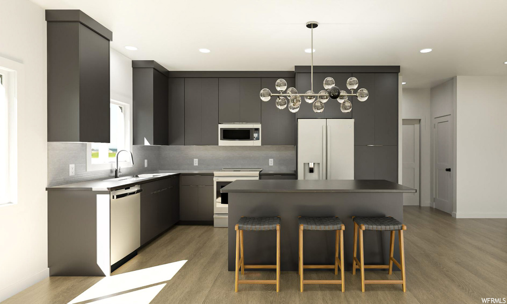 Kitchen with light hardwood / wood-style floors, a kitchen bar, tasteful backsplash, white appliances, and a kitchen island