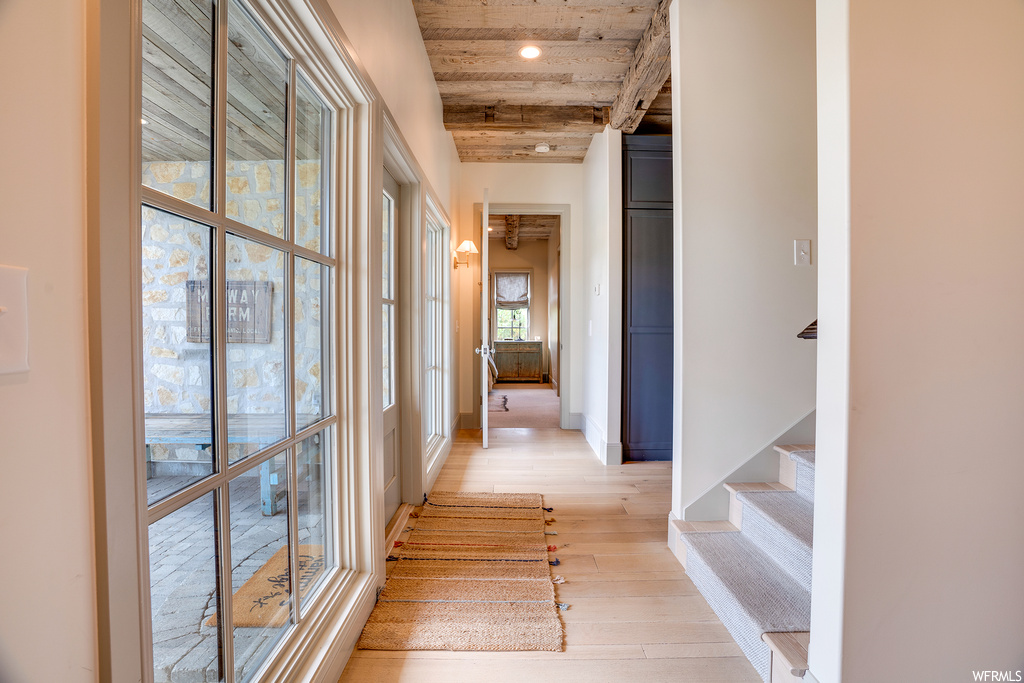 Corridor with light hardwood floors and wooden ceiling