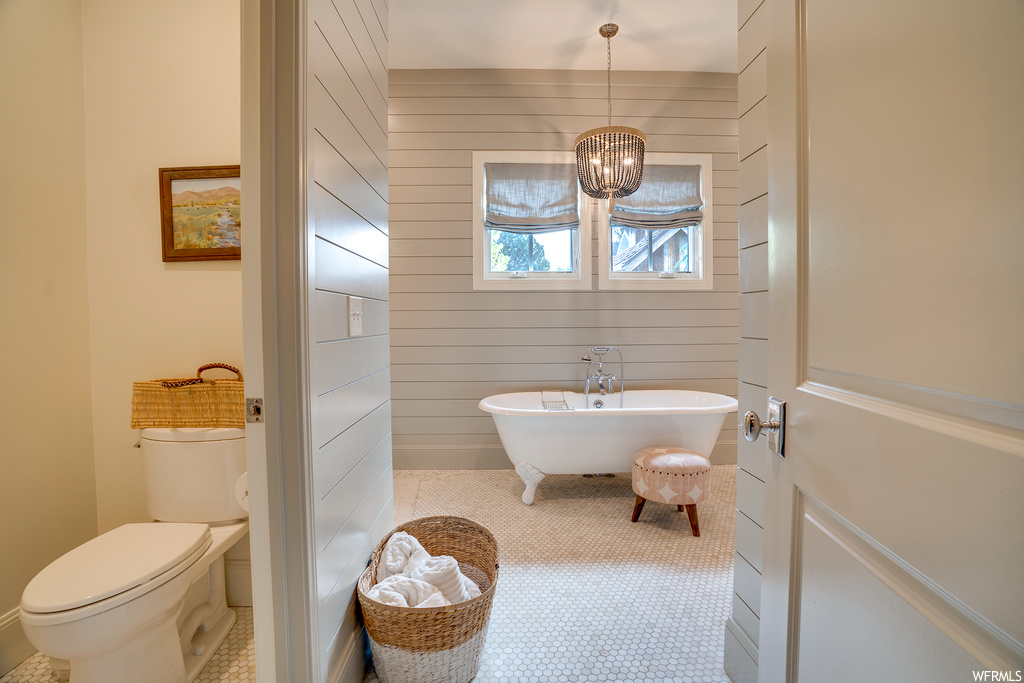 Bathroom featuring wood walls, light tile flooring, and a bathtub