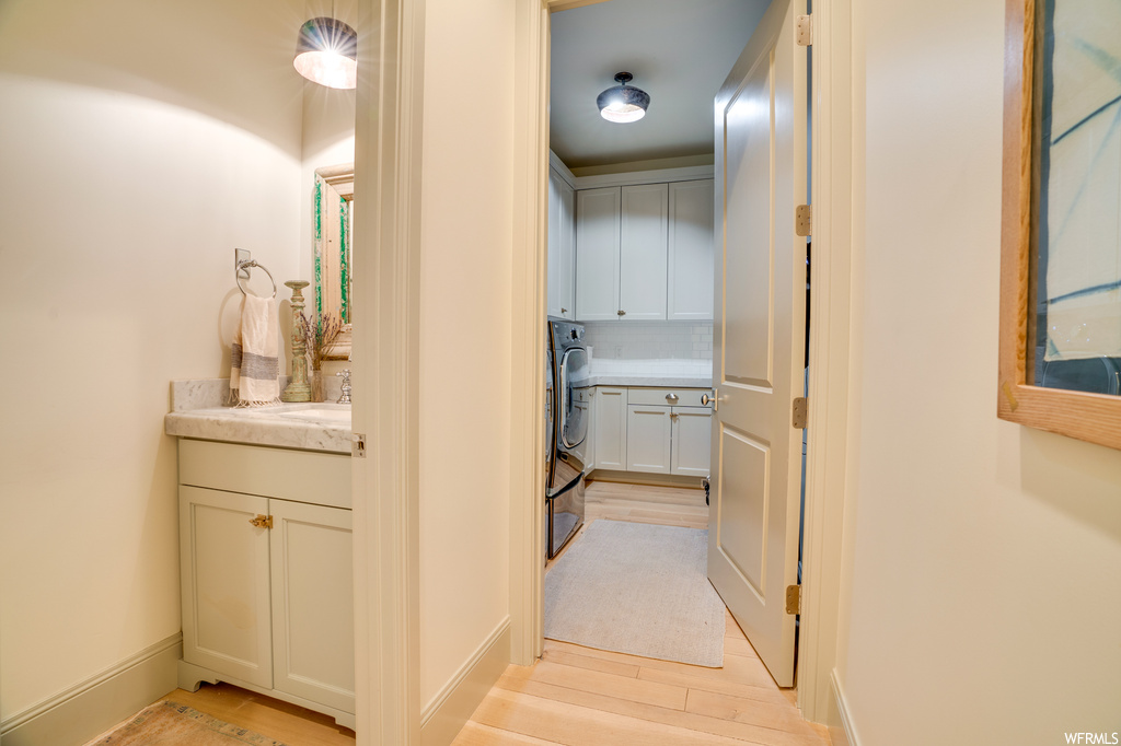 Hallway with washer / clothes dryer and light hardwood floors