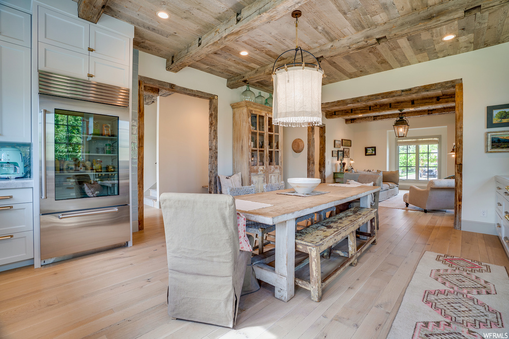Dining room with wooden ceiling, beam ceiling, and light hardwood floors