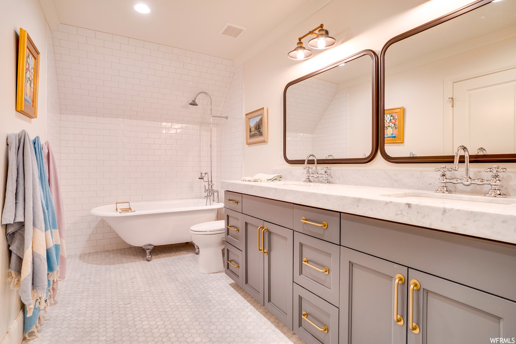 Full bathroom with mirror, tiled shower / bath, light tile floors, dual large bowl vanity, and tile walls