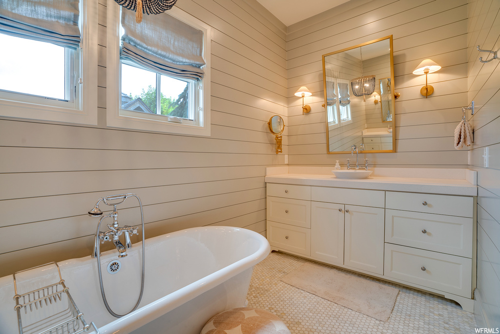 Bathroom featuring vanity, a bathing tub, mirror, wood walls, and light tile floors