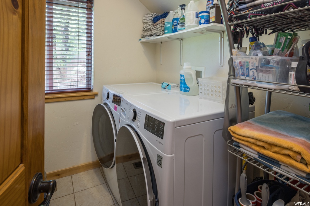 Laundry area featuring separate washer and dryer and light tile floors