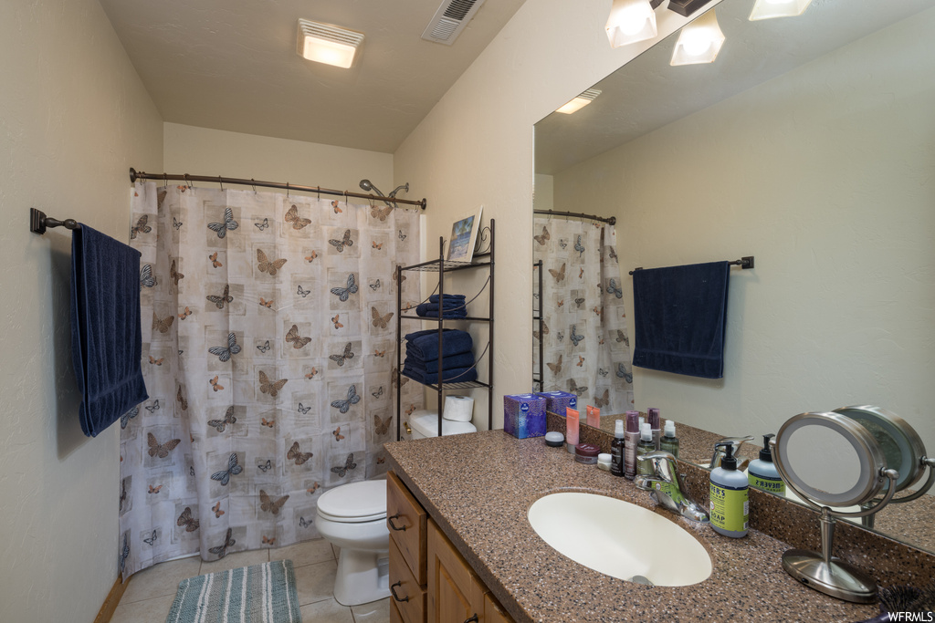 Bathroom with large vanity, mirror, and light tile floors