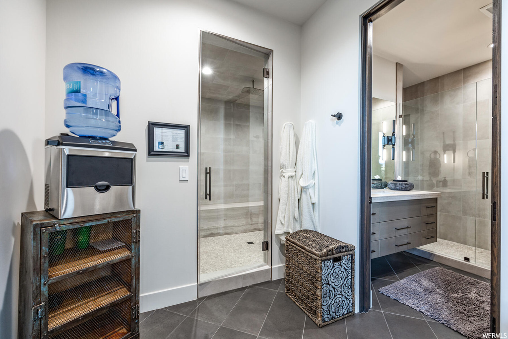 Bathroom with dark tile flooring, a shower with door, and vanity