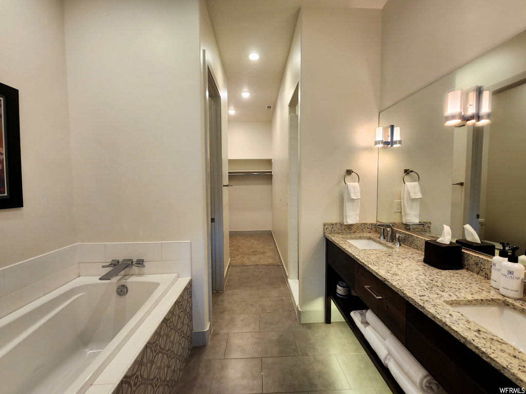 Bathroom with tile floors, dual large bowl vanity, tiled tub, and mirror