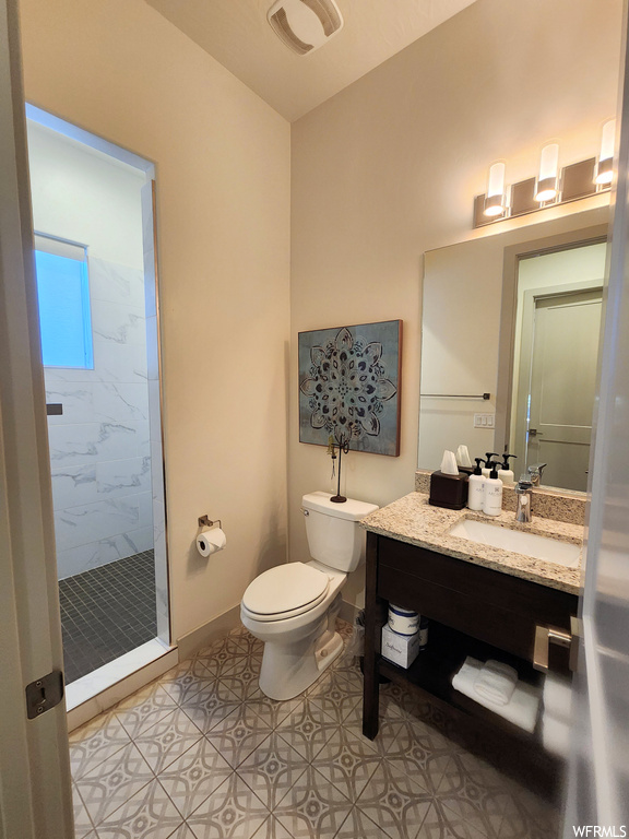 Bathroom featuring tiled shower, light tile floors, mirror, and vanity