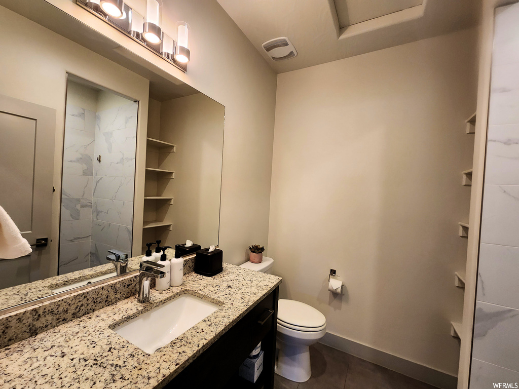Bathroom featuring dark tile floors, vanity, and mirror