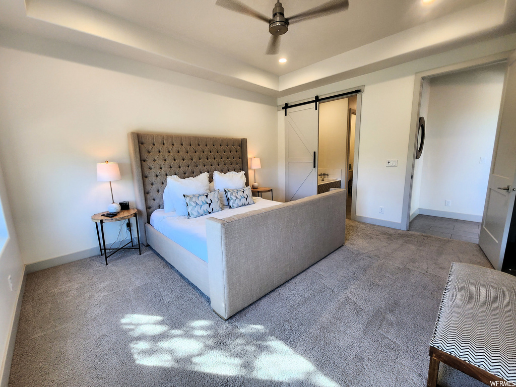 Bedroom with light carpet, ceiling fan, and a raised ceiling