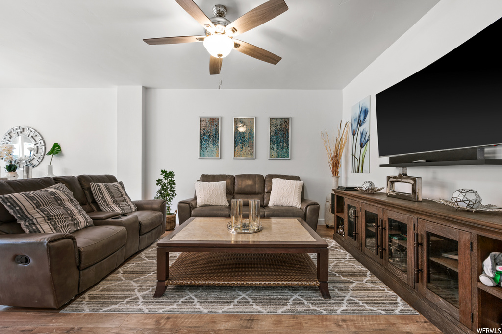 Hardwood floored living room featuring ceiling fan