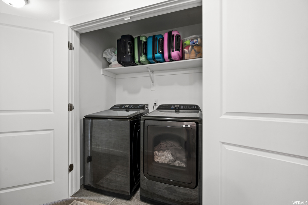 Clothes washing area featuring tile flooring and washer and clothes dryer