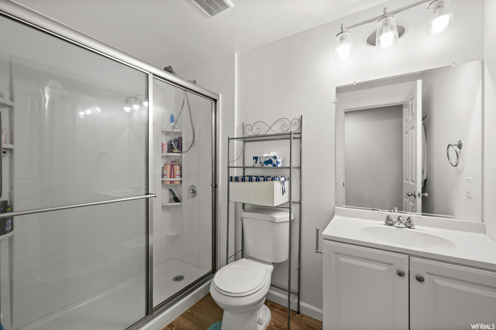 Bathroom featuring an enclosed shower, large vanity, wood-type flooring, and mirror