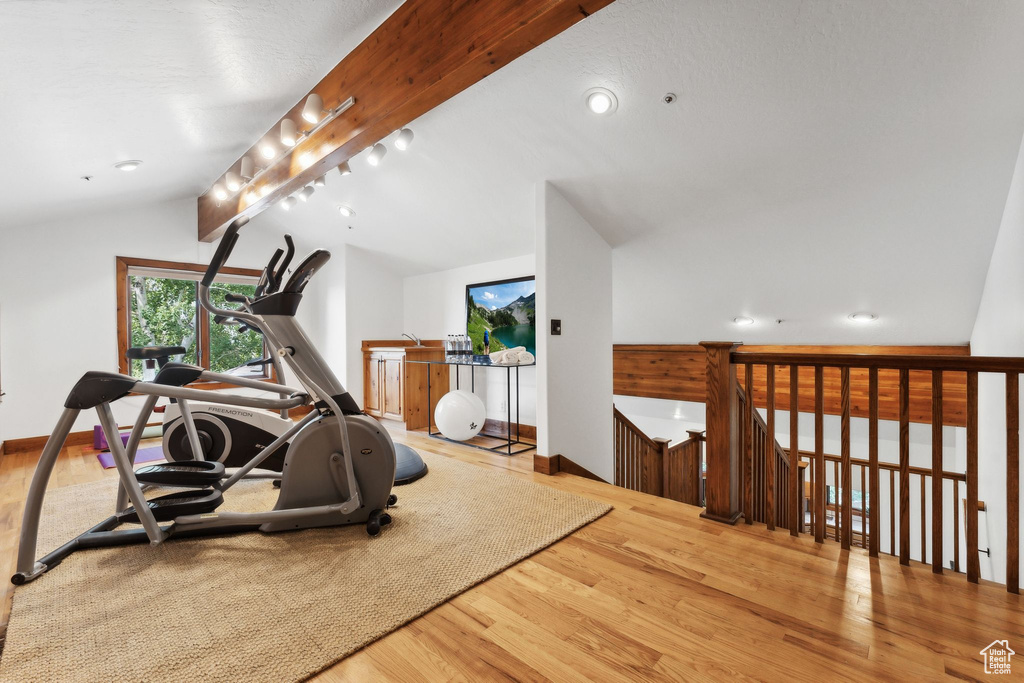 Workout area with track lighting, light hardwood / wood-style flooring, and lofted ceiling