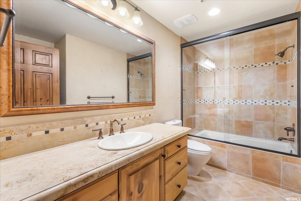 Full bathroom with vanity, enclosed tub / shower combo, mirror, backsplash, and light tile floors