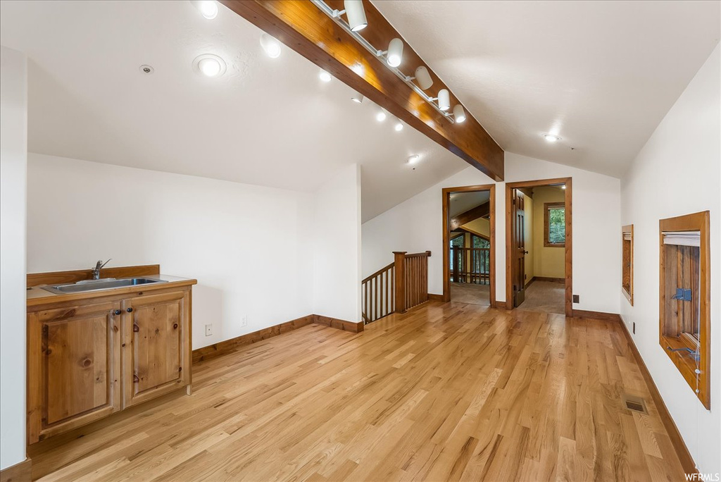Bonus room featuring lofted ceiling with beams and light hardwood flooring