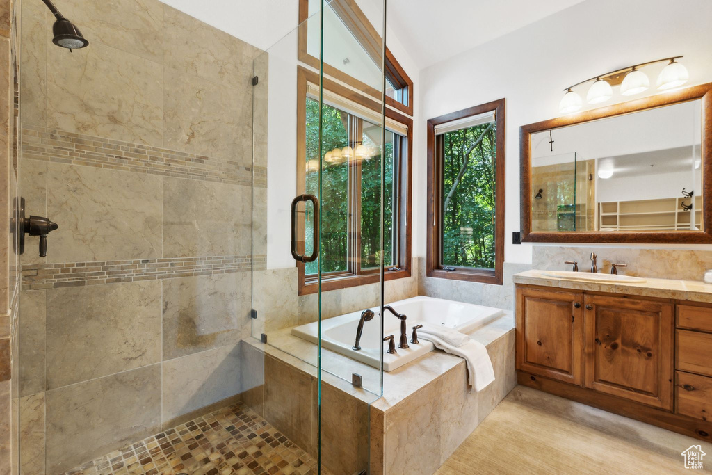 Bathroom featuring vanity, separate shower and tub, tasteful backsplash, and tile walls