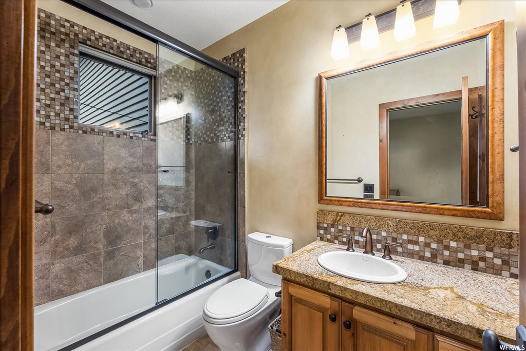 Full bathroom with large vanity, combined bath / shower with glass door, mirror, and backsplash