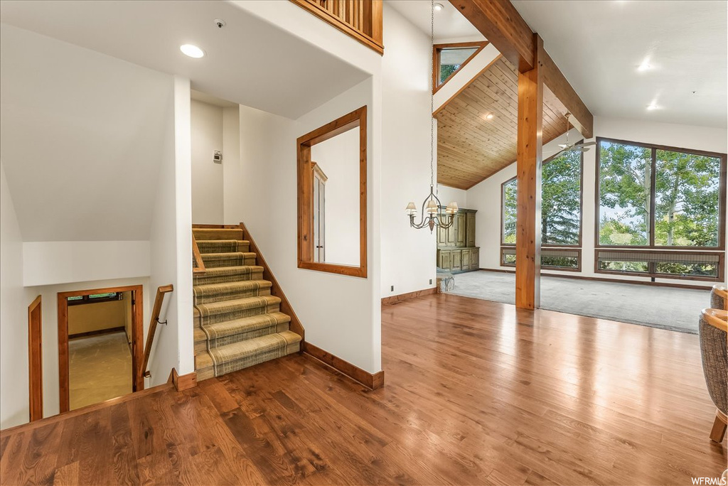 Stairs featuring lofted ceiling with beams, light hardwood floors, and a high ceiling