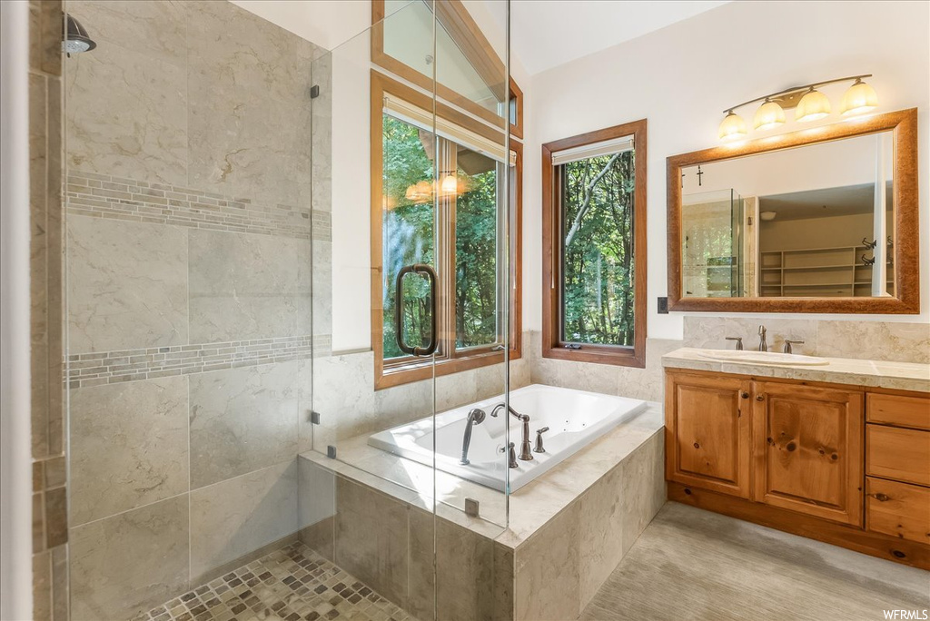 Bathroom with vanity, separate shower and tub enclosures, mirror, and tile walls