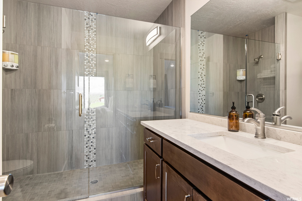 Bathroom with an enclosed shower, large vanity, and mirror