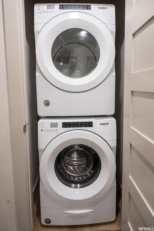 Washroom with stacked washer and dryer and dark hardwood floors