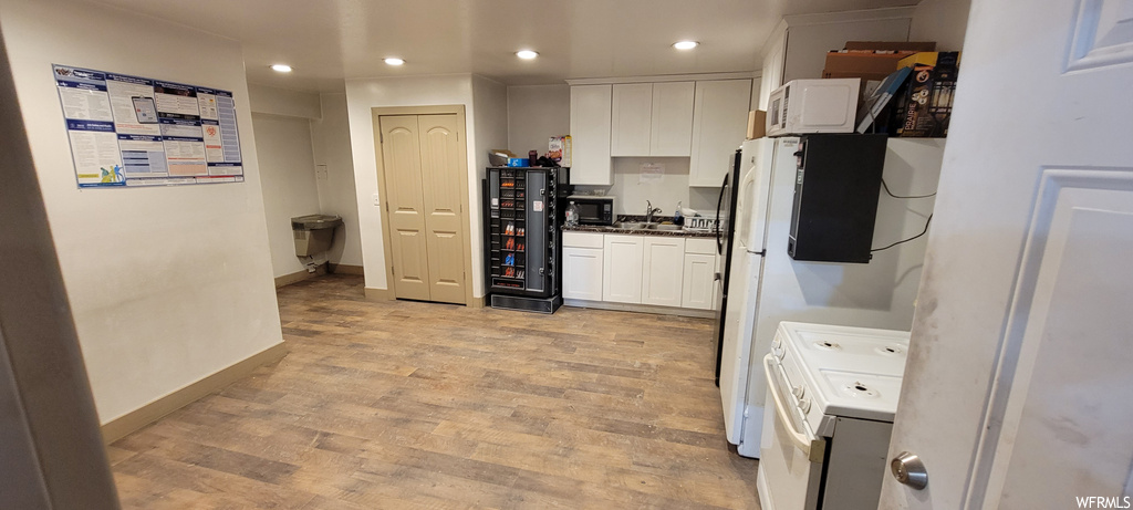 Kitchen with light hardwood flooring, white range, and white cabinets