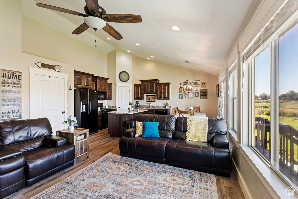Living room featuring vaulted ceiling, dark hardwood / wood-style flooring, and ceiling fan with notable chandelier