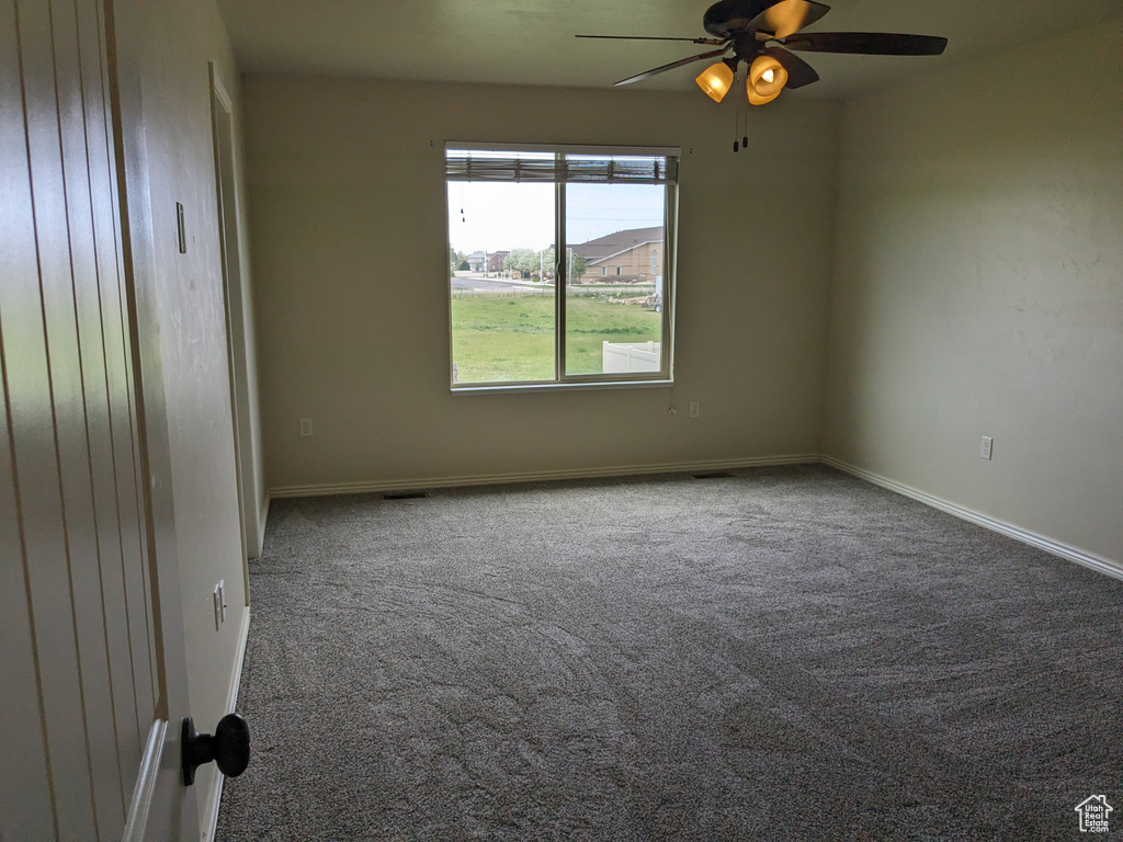 Empty room featuring ceiling fan and carpet flooring
