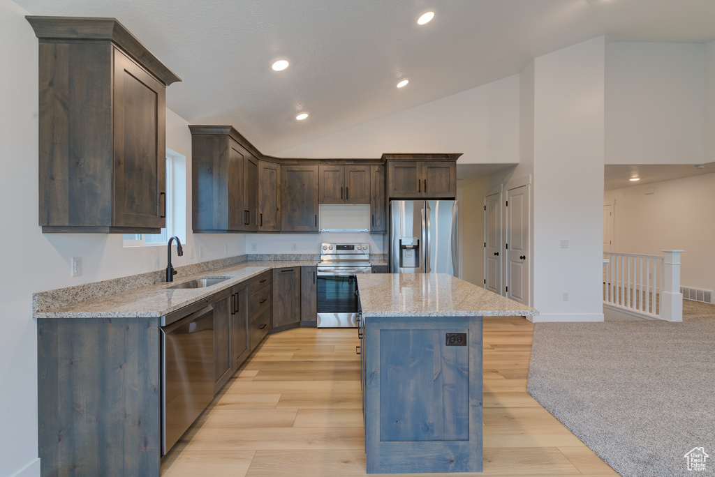 Kitchen featuring a center island, light wood-type flooring, stainless steel appliances, and light stone counters