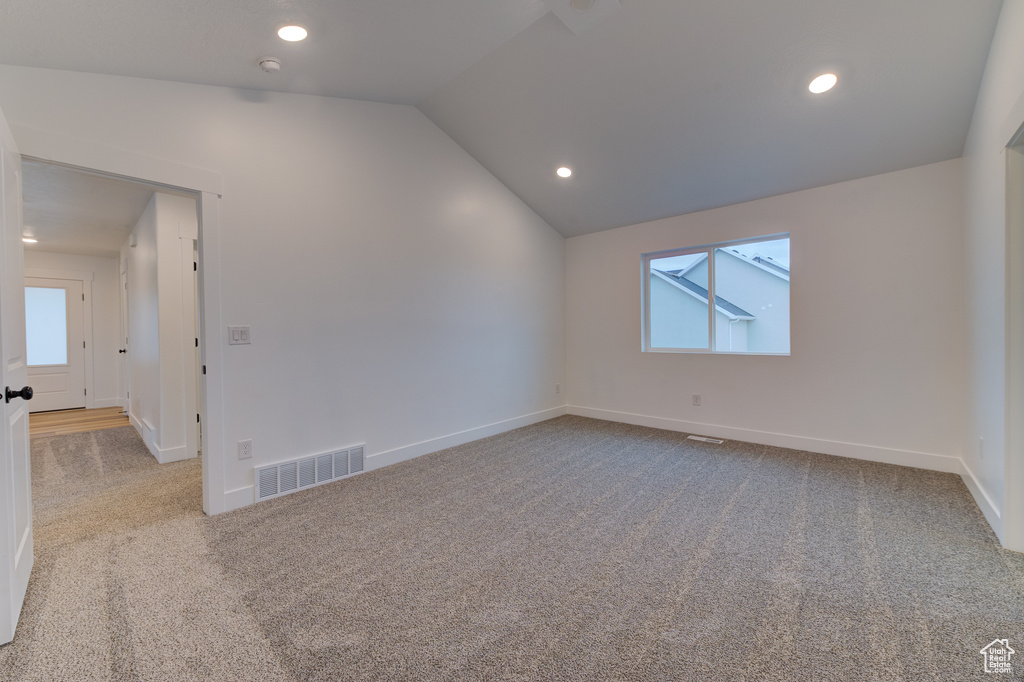 Empty room featuring lofted ceiling and light carpet