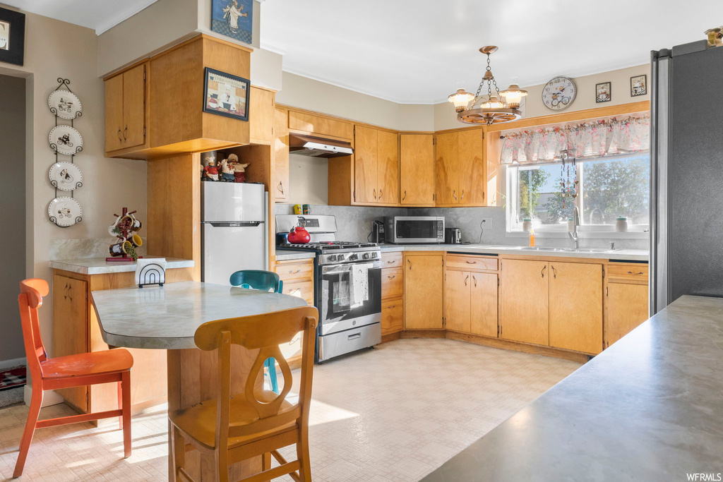 Kitchen with backsplash, brown cabinets, light countertops, and stainless steel appliances