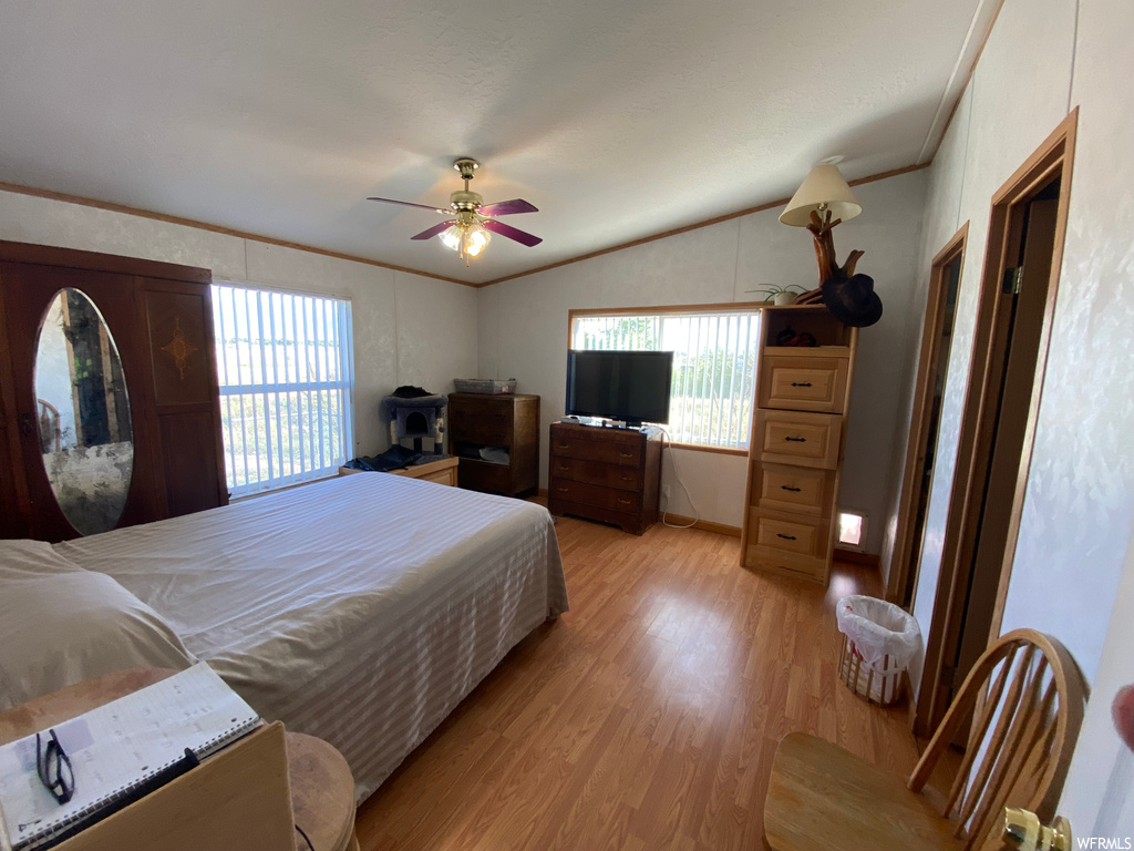 Bedroom with ceiling fan, light hardwood flooring, ornamental molding, and lofted ceiling
