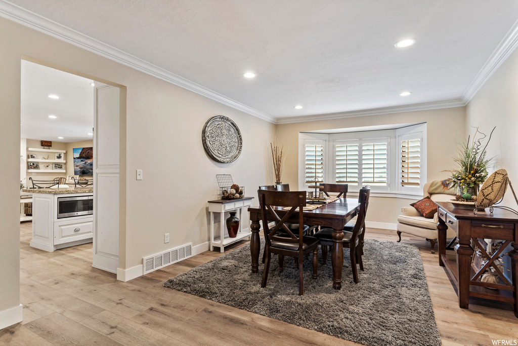 Dining space with crown molding and light hardwood flooring
