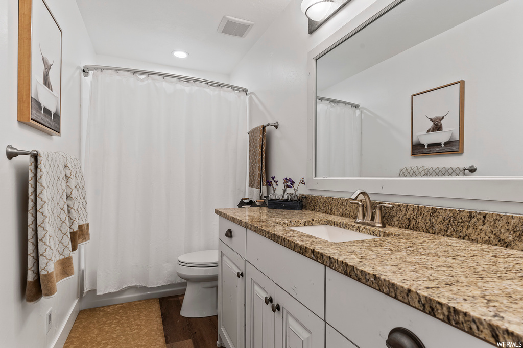 Full bathroom featuring large vanity, light hardwood floors, shower / tub combo with curtain, and mirror