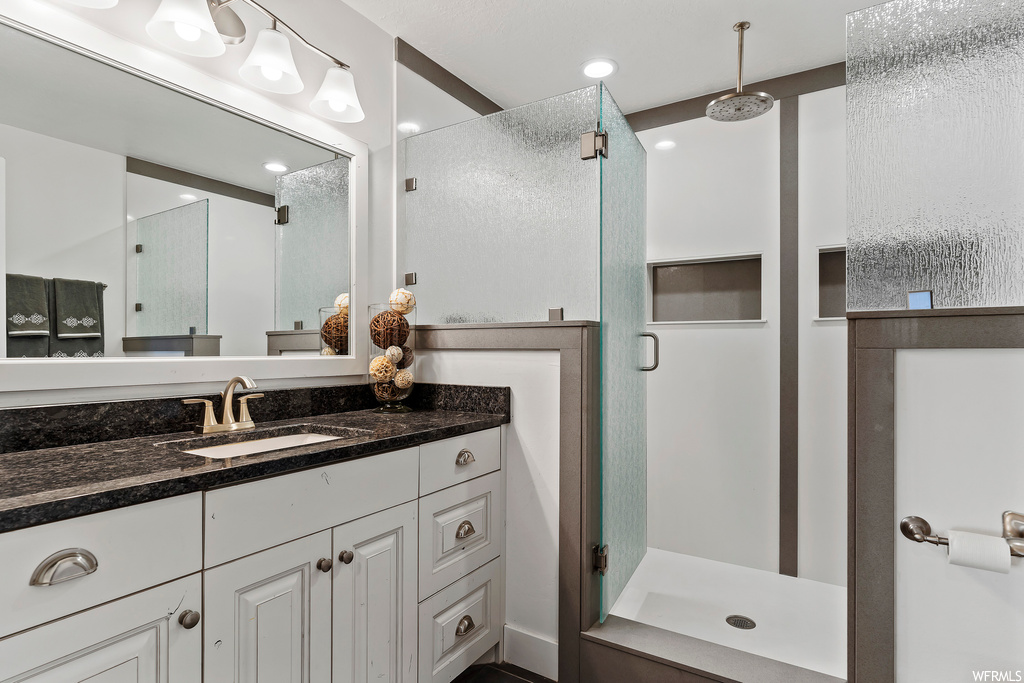 Bathroom with an enclosed shower, vanity, and mirror