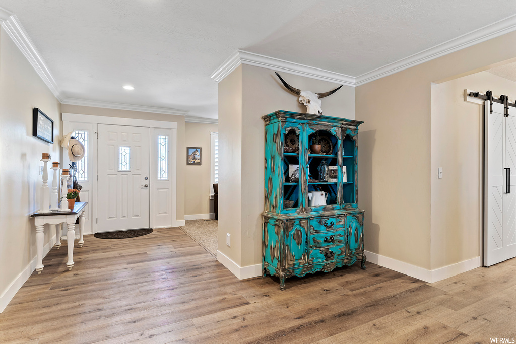 Hardwood floored foyer entrance with crown molding