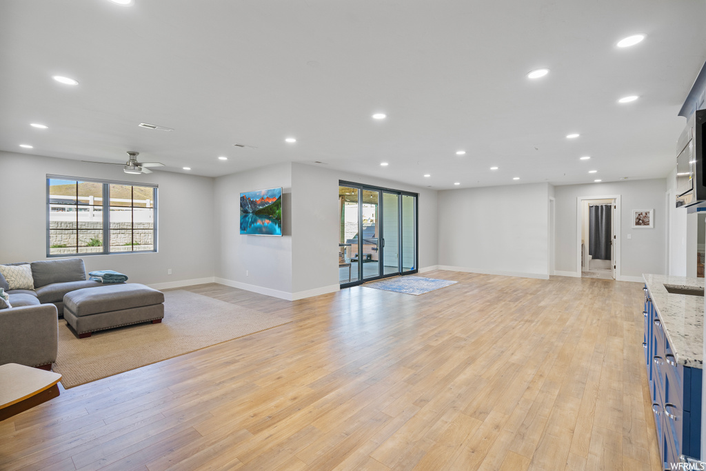 Living room featuring a wealth of natural light, light hardwood floors, and ceiling fan
