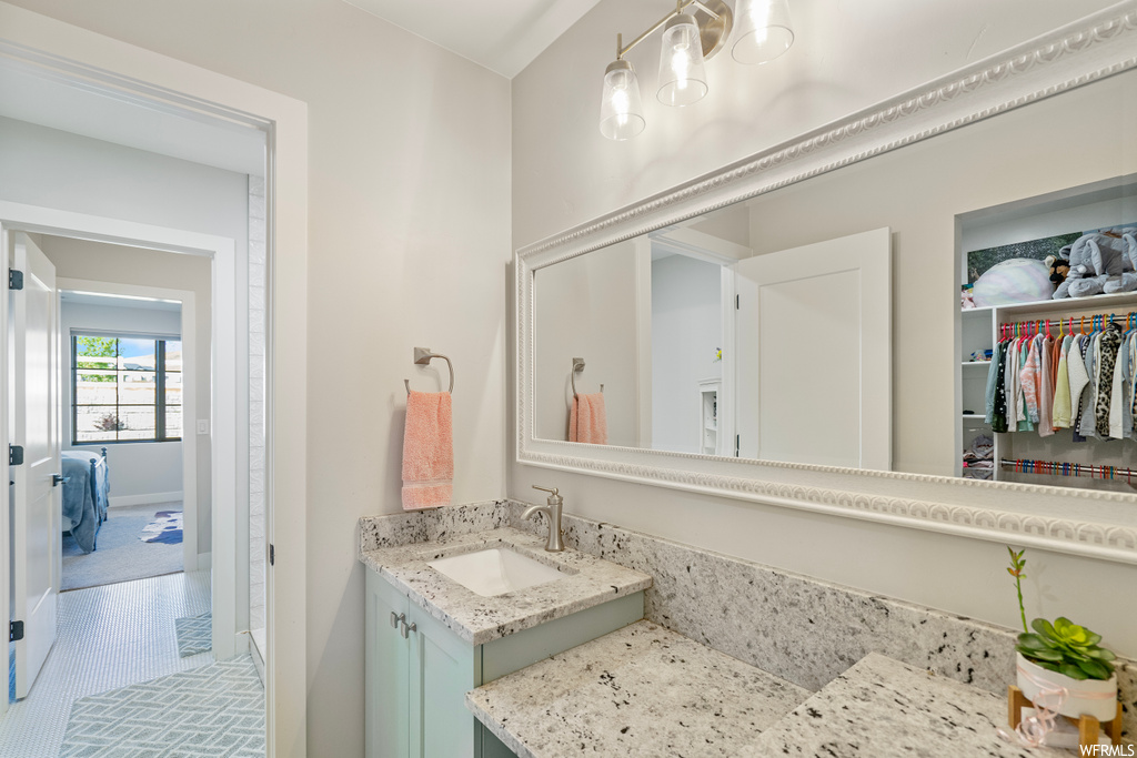 Bathroom with vanity, mirror, and light tile flooring