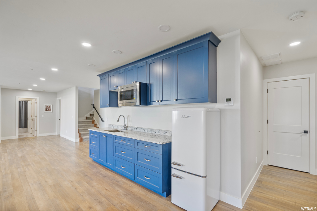 Kitchen featuring white fridge, light countertops, and light hardwood floors