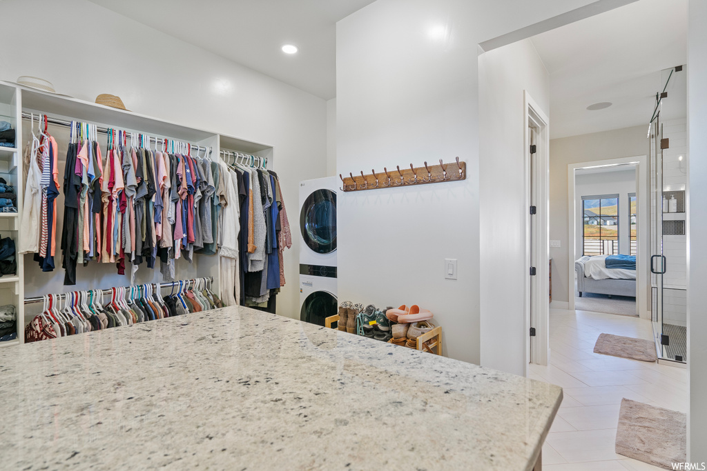 Wardrobe featuring stacked washer / drying machine and light tile flooring