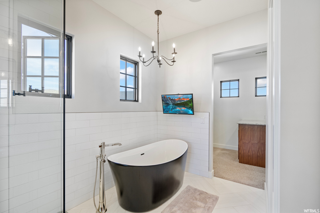Bathroom with vanity, plenty of natural light, a washtub, tile walls, and light tile floors