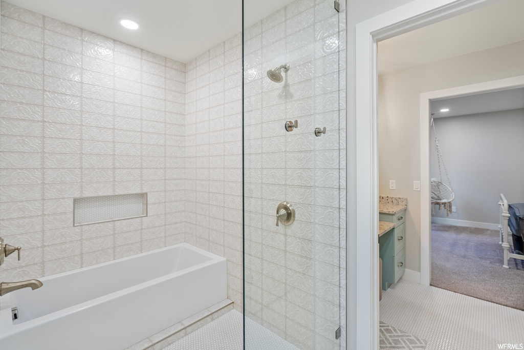 Bathroom featuring a shower with shower door, light tile floors, and vanity