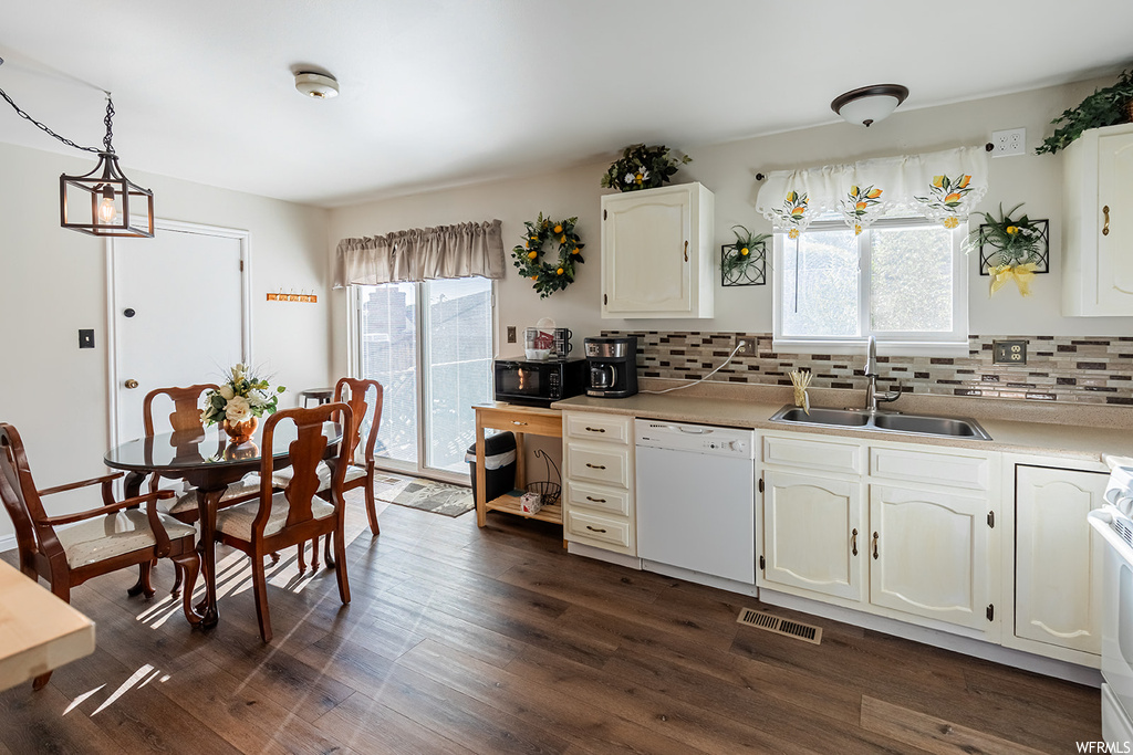 Kitchen featuring dark hardwood floors, range, backsplash, light countertops, white cabinetry, and white dishwasher