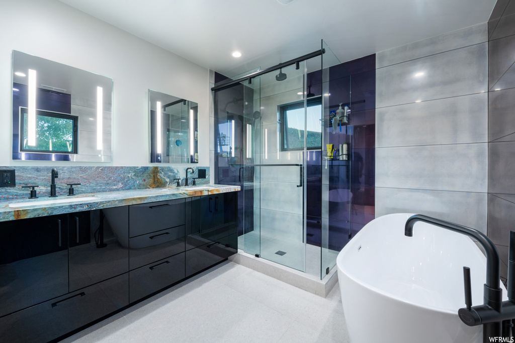 Bathroom featuring plenty of natural light, double large vanity, mirror, shower with separate bathtub, and light tile floors