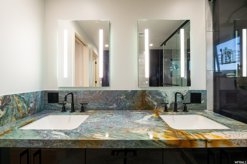 Bathroom featuring backsplash, dual vanity, and mirror