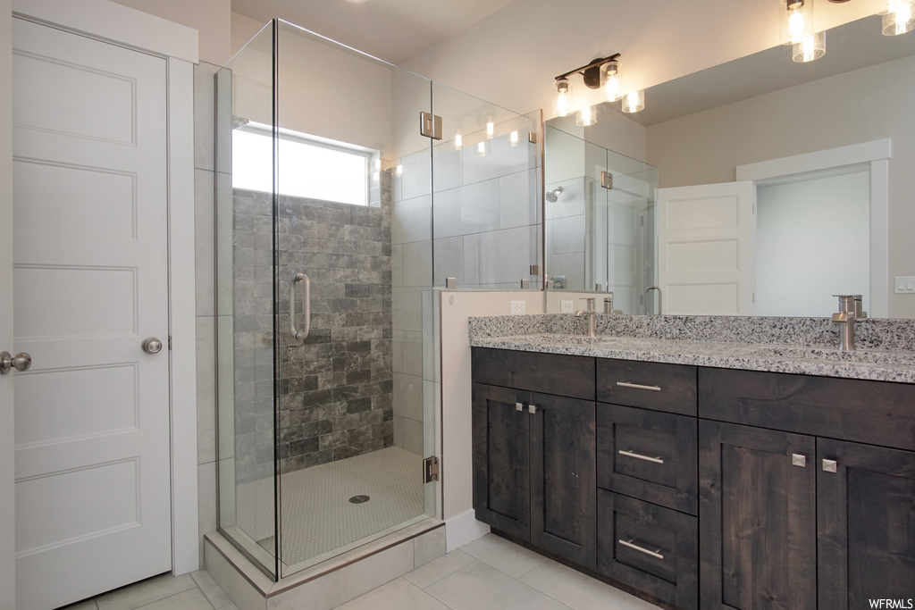 Bathroom featuring an enclosed shower, vanity, light tile flooring, and mirror