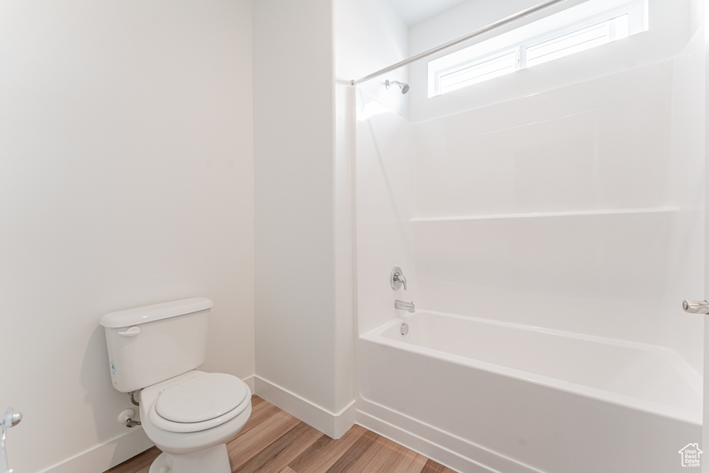 Bathroom featuring hardwood / wood-style flooring, shower / bath combination, and toilet