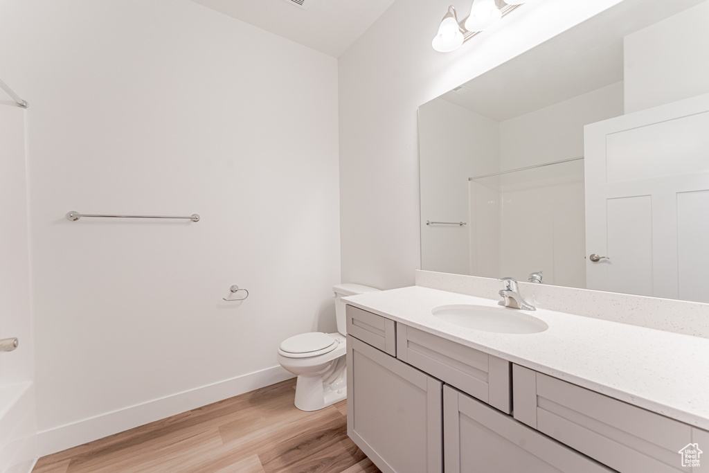 Full bathroom featuring wood-type flooring, shower / bathing tub combination, vanity, and toilet