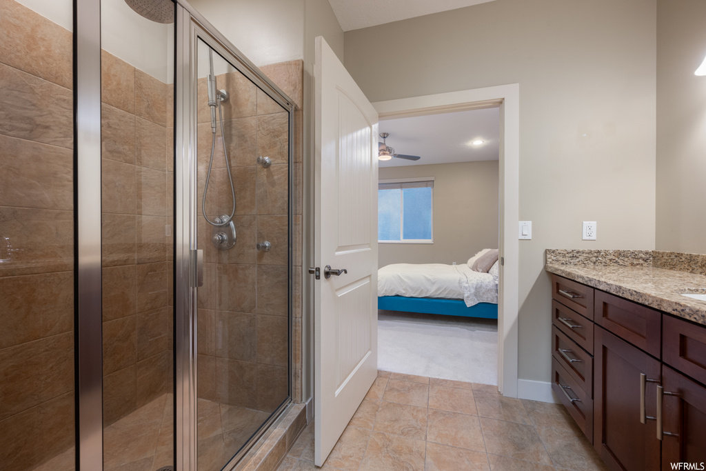 Bathroom featuring an enclosed shower, vanity, light tile flooring, and ceiling fan